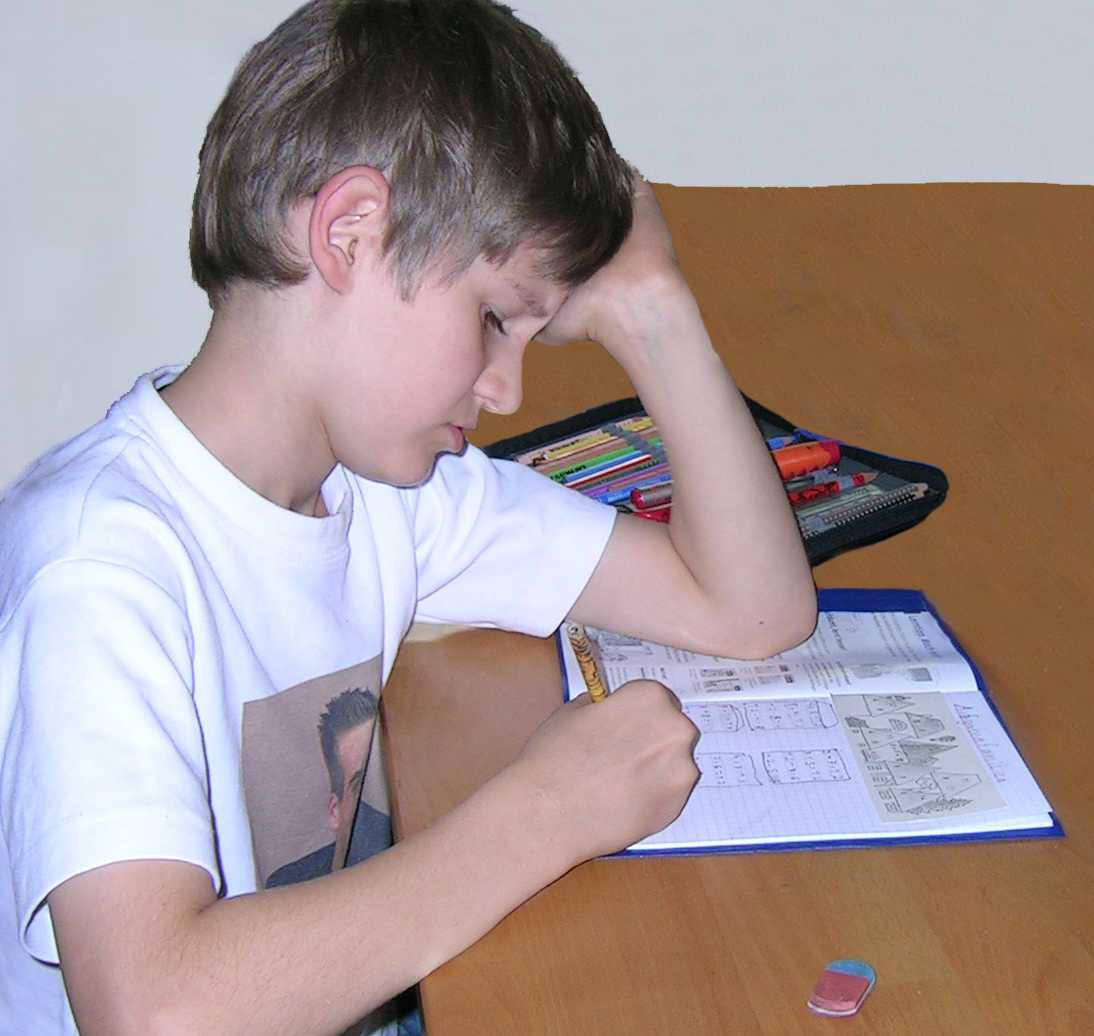 Bild: Ein Schulkind sitzt am Tisch und schreibt Hausaufgaben